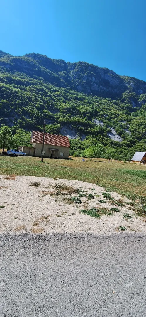 Pogled na kuću i imanje sa planinskim pejzažom u pozadini.