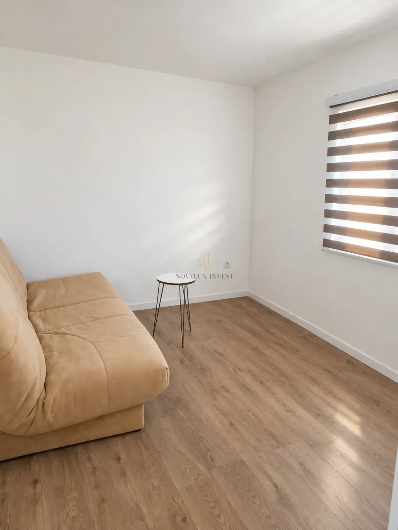 Small living room with a beige sofa, small coffee table, and a window with blinds.