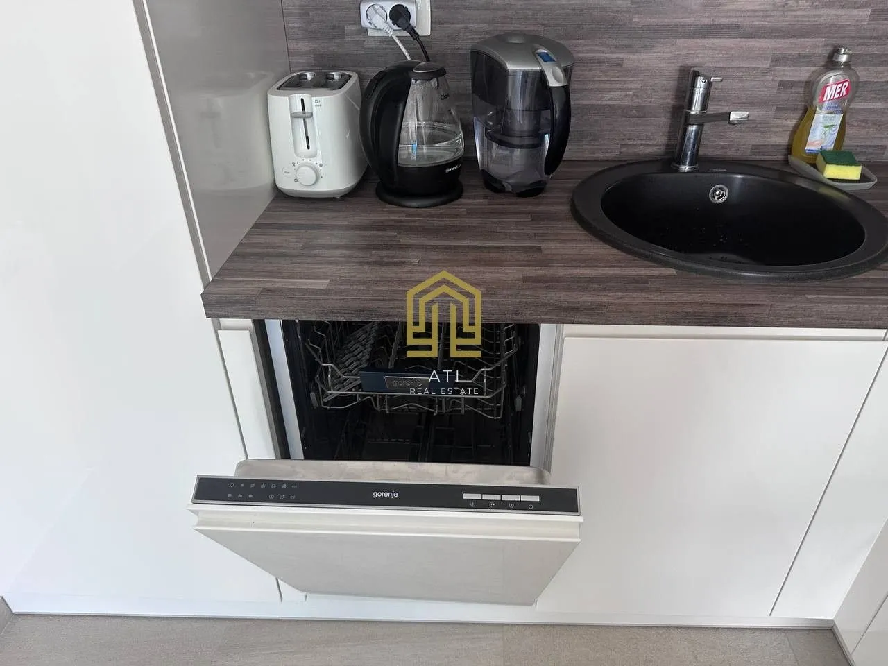 Part of a modern kitchen with a built-in dishwasher and countertop.