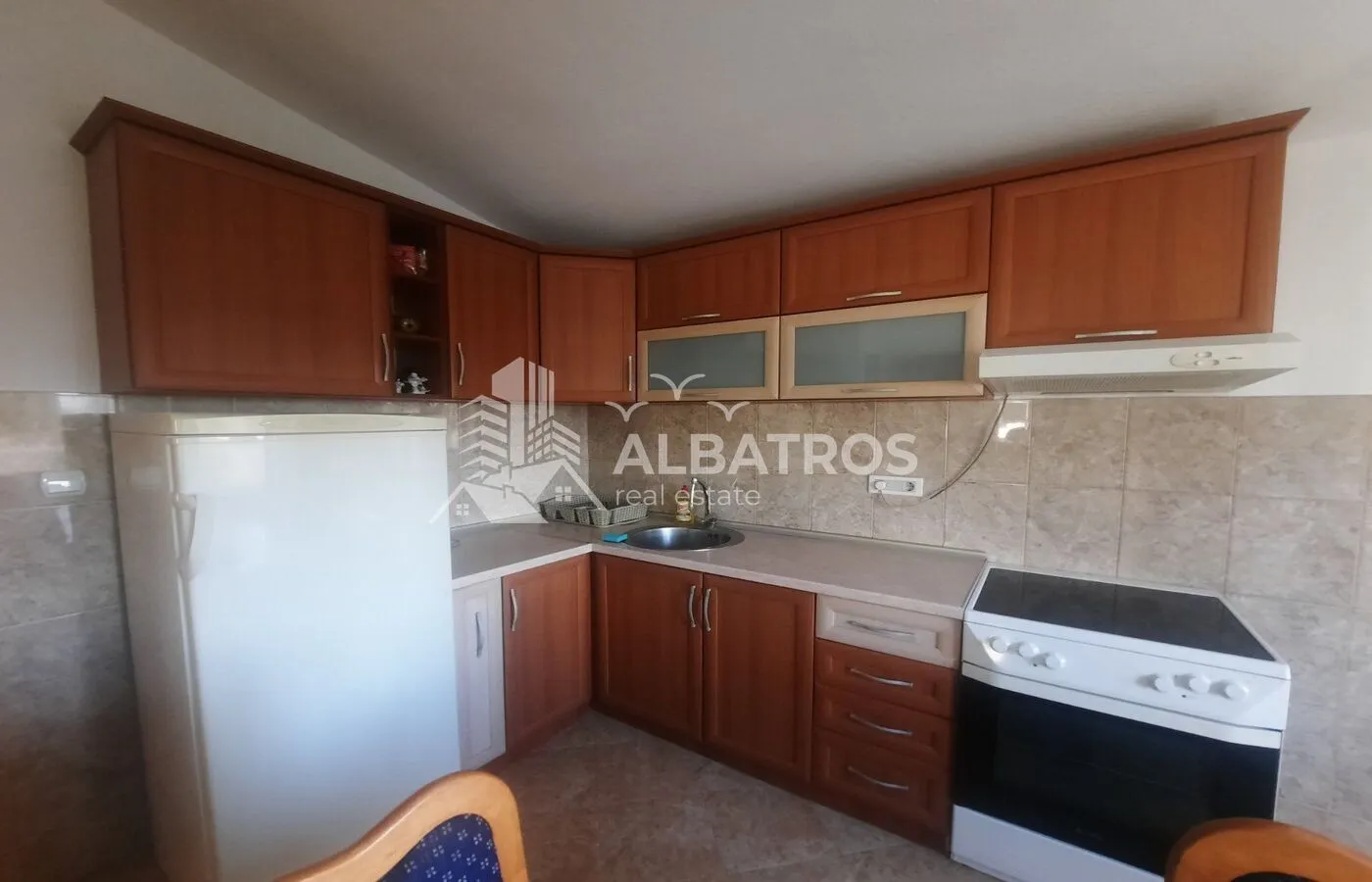 Kitchen with wooden cabinetry, refrigerator, and stove.