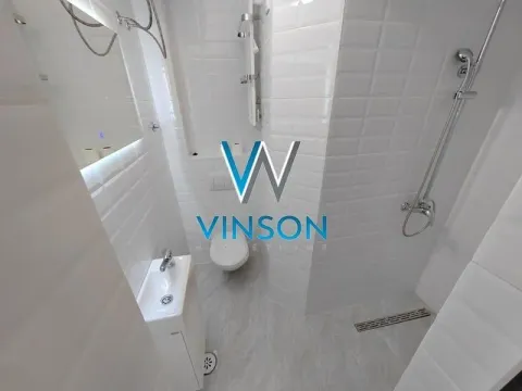 Manje kupatilo sa belim pločicama, tuš kabinom, WC šoljom i umivaonikom. - image 6