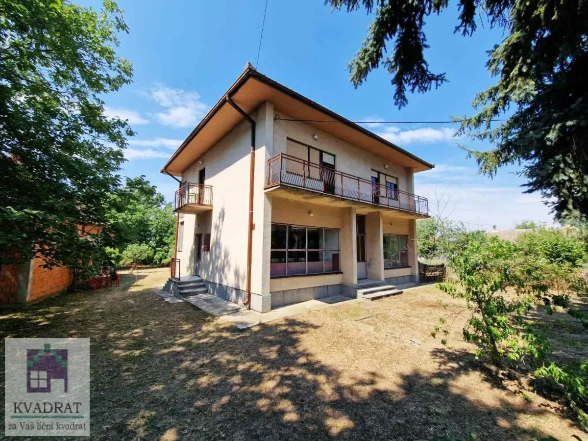 Pogled na dvospratnu kuću sa dvorištem i terasama.