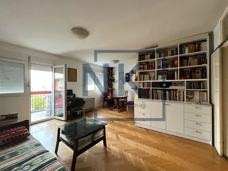 Dnevna soba sa parketom, velikom bijelom bibliotekom i izlazom na terasu.