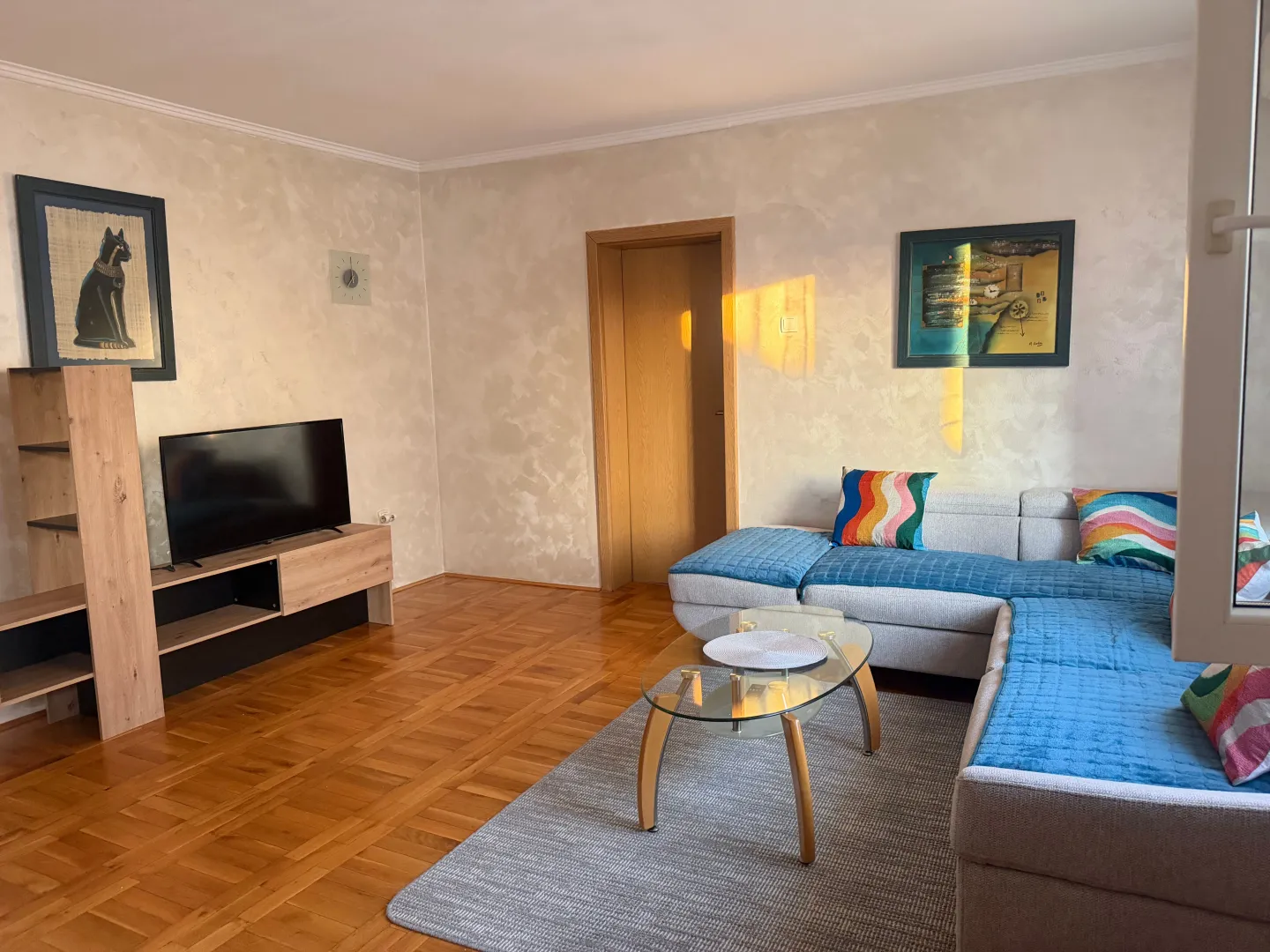 Living room with a corner sofa, television, and wooden floor.