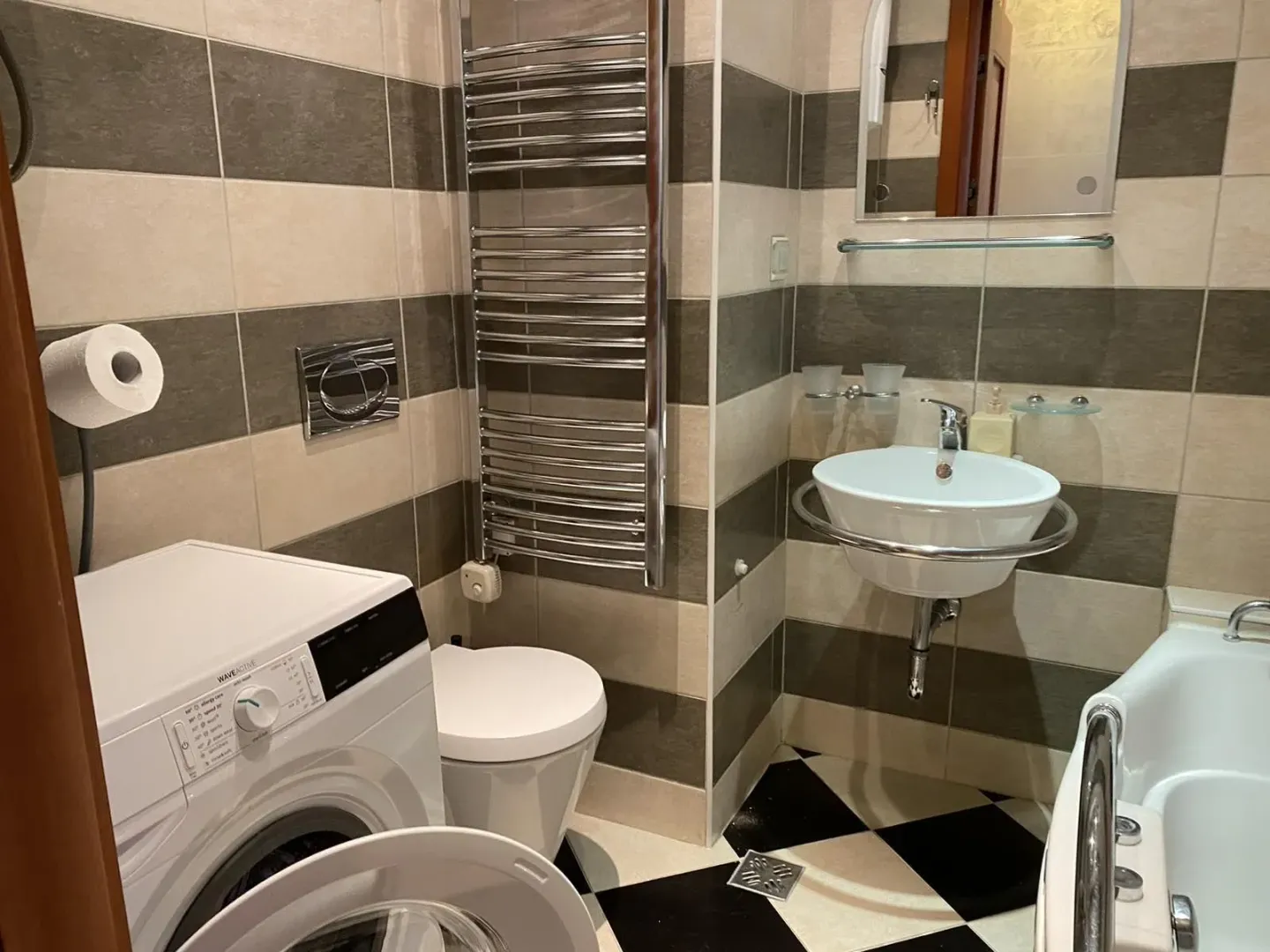A bathroom with a washing machine, toilet, and sink.