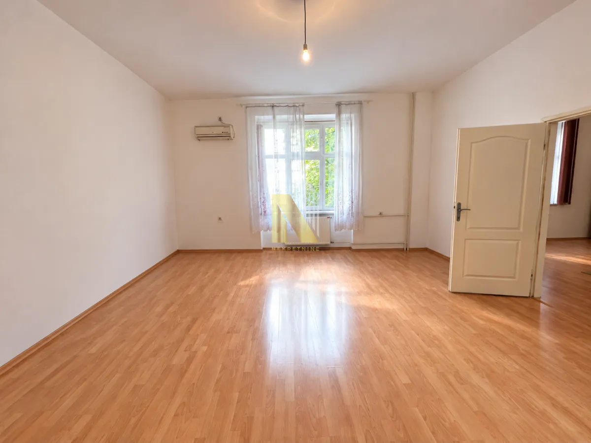 Empty room with hardwood flooring and an open door.