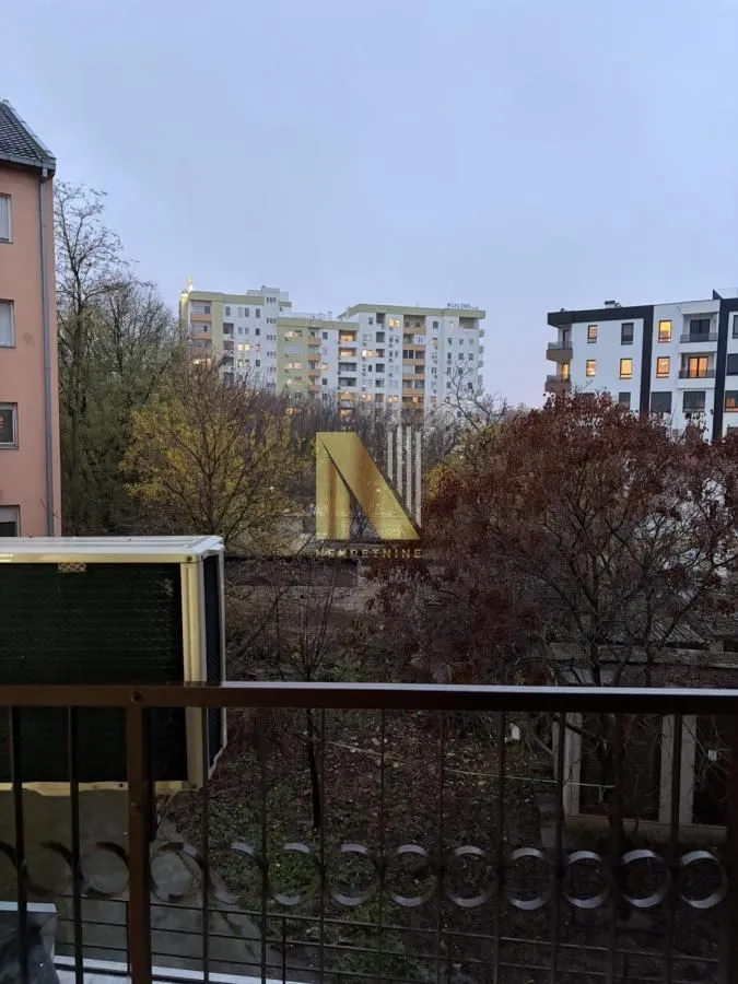 Pogled sa terase na okolne zgrade i drveće.