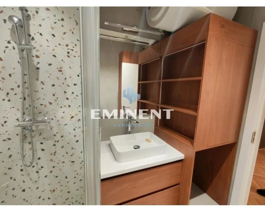 Modern bathroom with a shower cabin and a wooden vanity unit with a washbasin.
