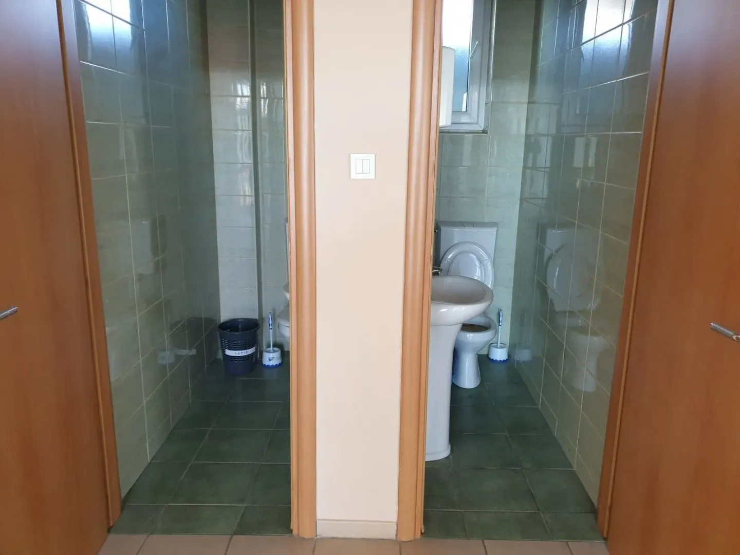 Two separate toilets with tiled walls and sanitary ware.