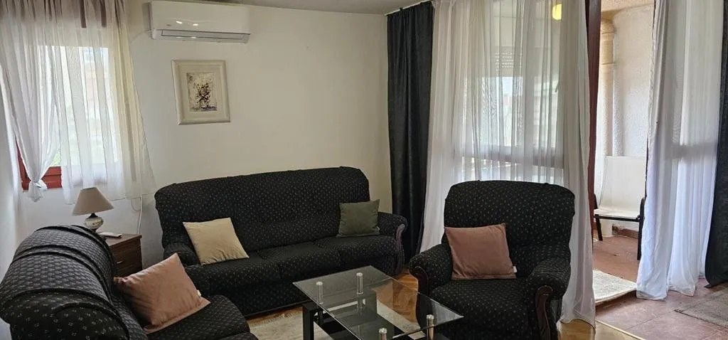 Dnevna soba sa garniturom za sjedenje i izlazom na terasu.