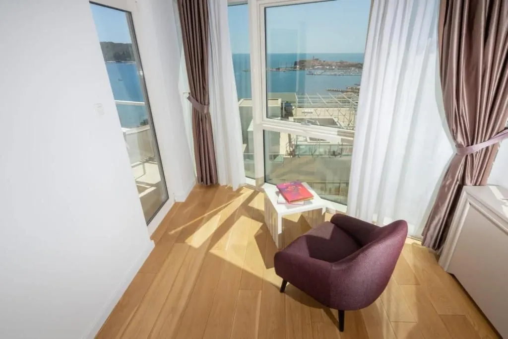 Living room with an armchair and sea view through large windows.