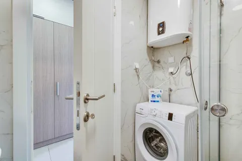 Small bathroom with a washing machine, water heater, and shower cabin. - image 19