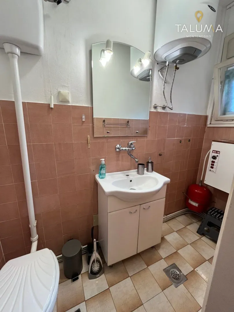 Smaller bathroom with a sink, mirror, and water heater.