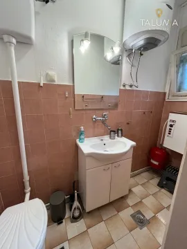 Smaller bathroom with a sink, mirror, and water heater. - image 11
