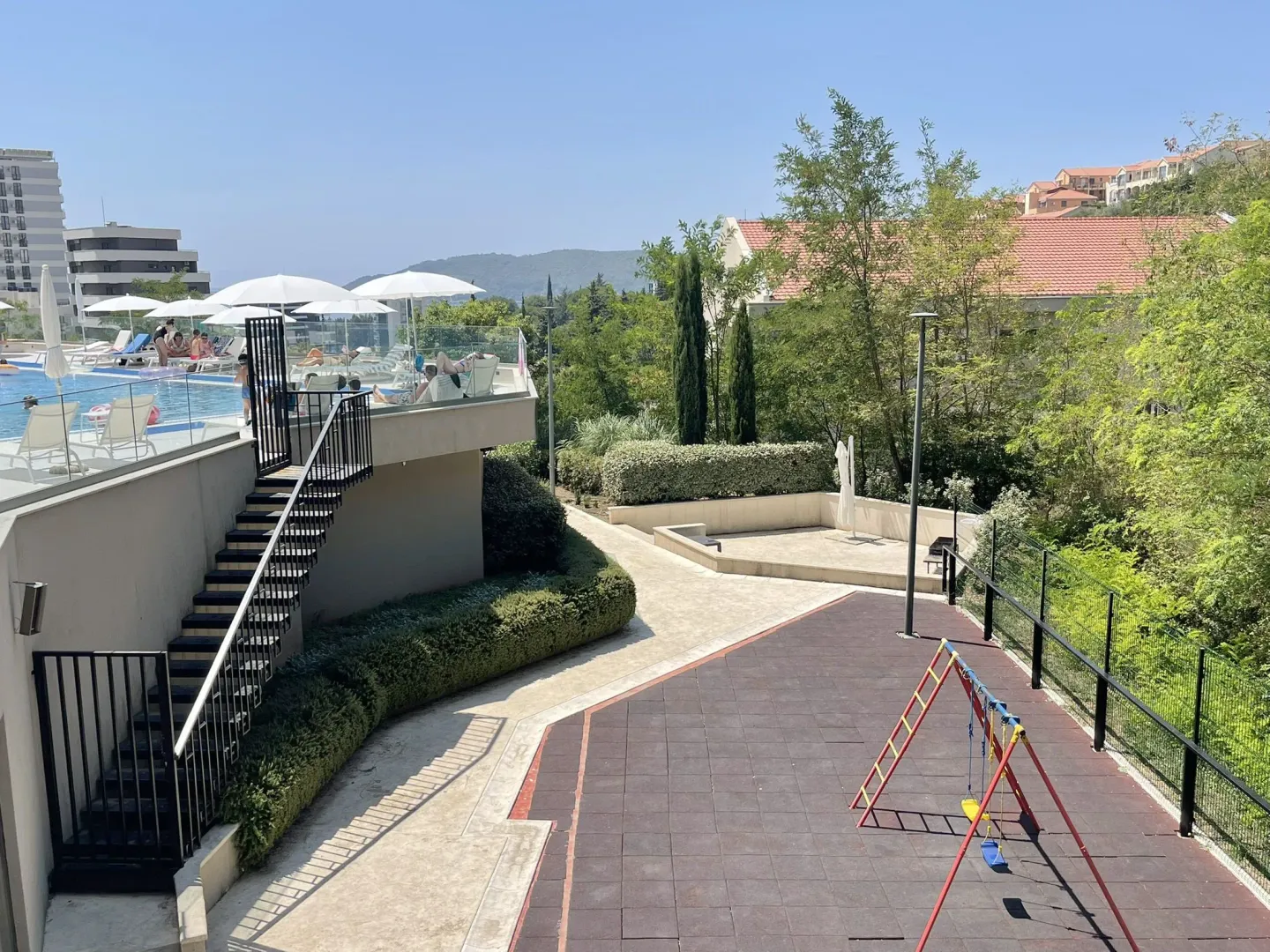 Exterior of the residential complex with a swimming pool and children's playground.