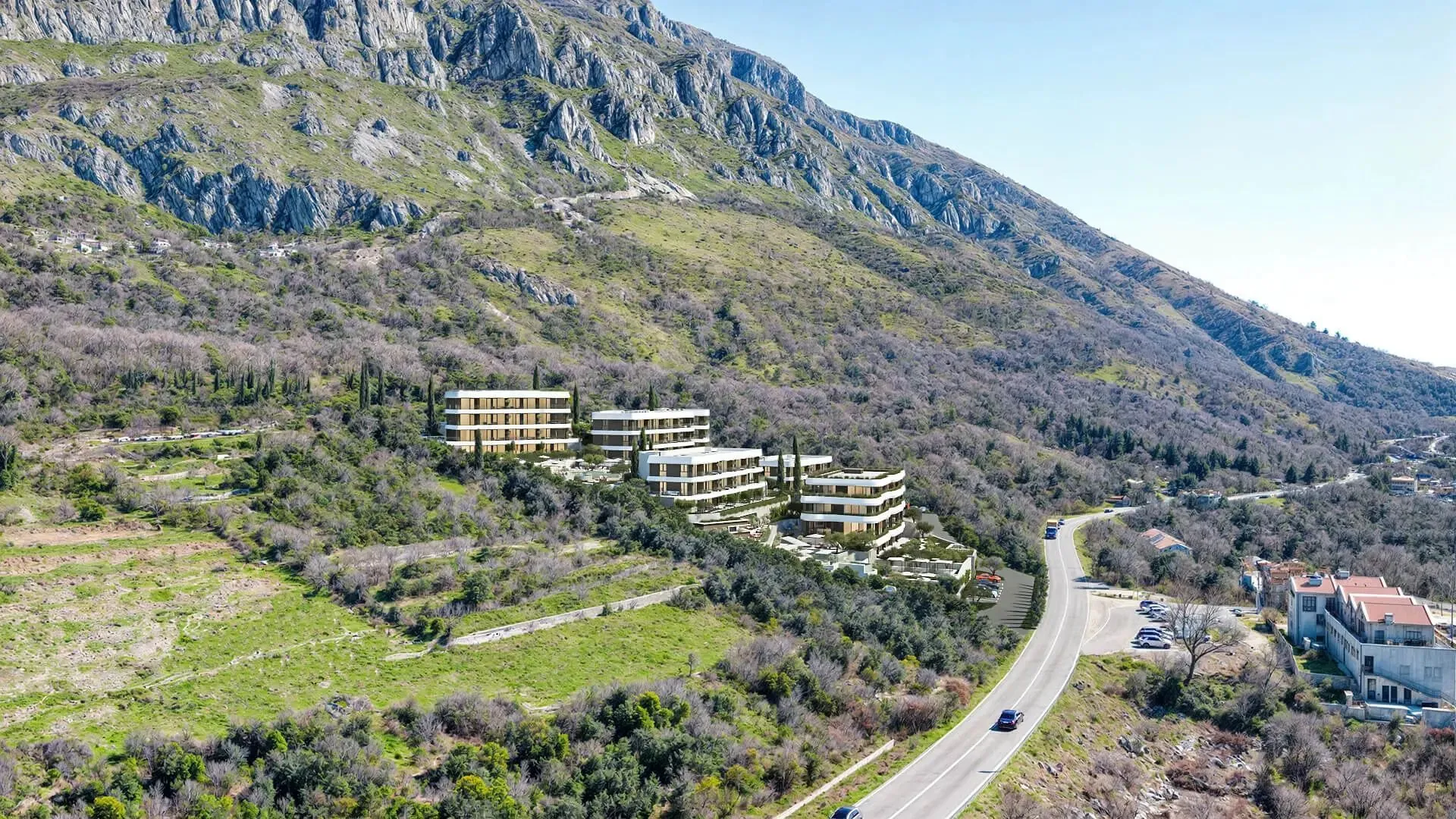 Pogled iz vazduha na kompleks zgrada smještenih u podnožju planine pored puta.