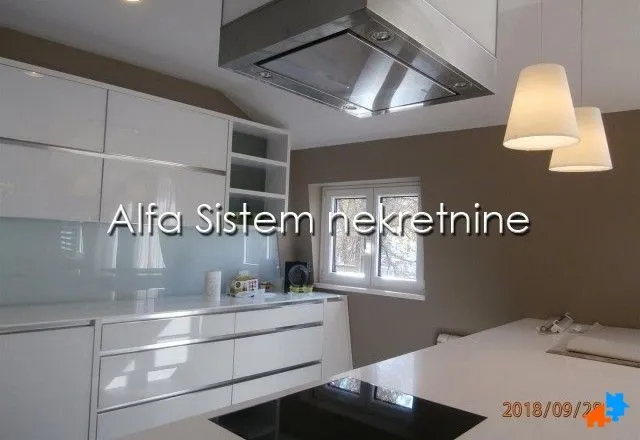 Modern white kitchen with an island and extractor hood.