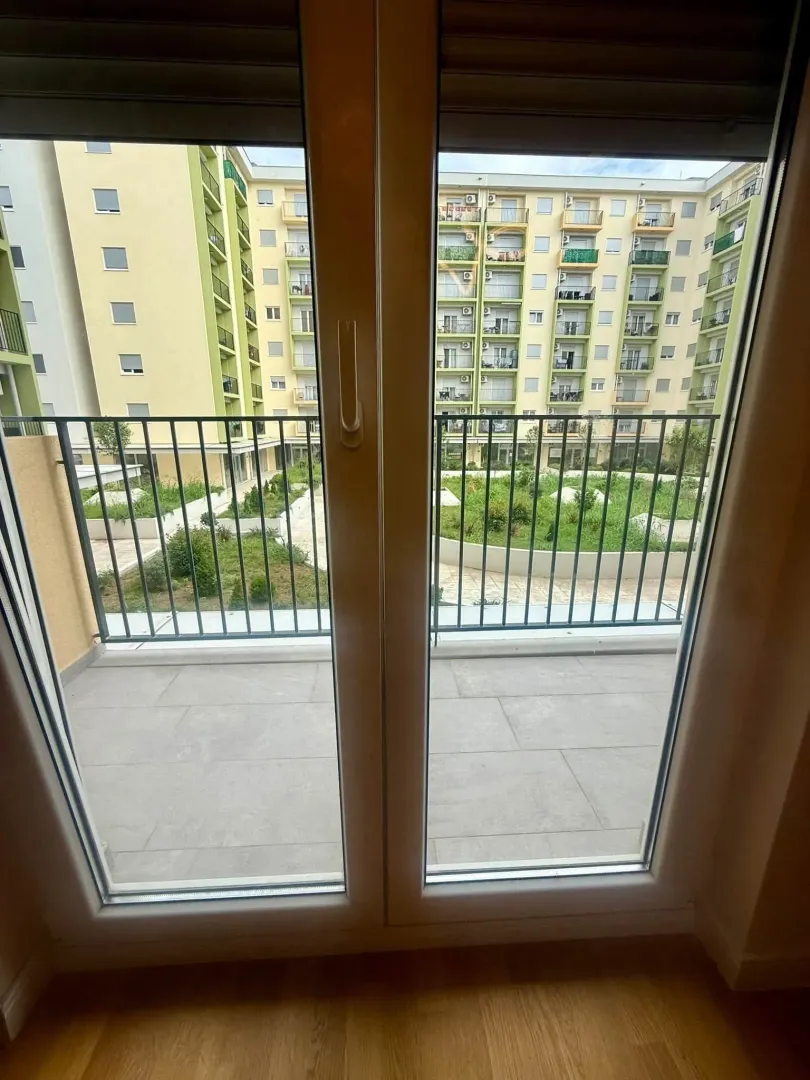 Pogled sa balkona na dvorište i okolne stambene zgrade.