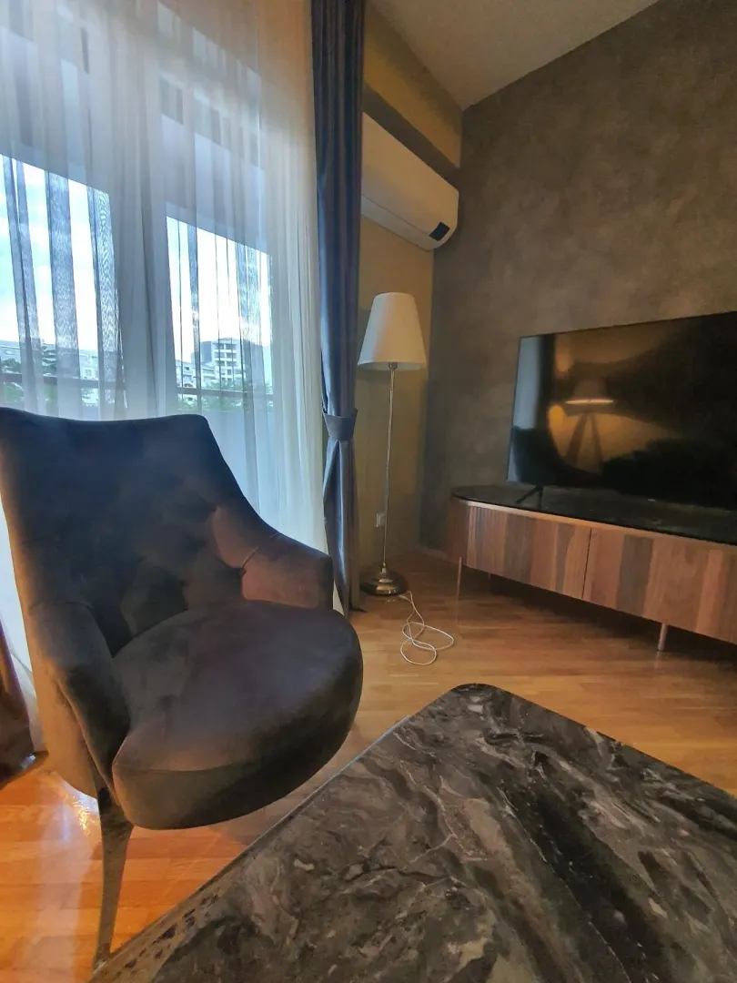 Dio dnevne sobe sa udobnom foteljom i TV komodom.