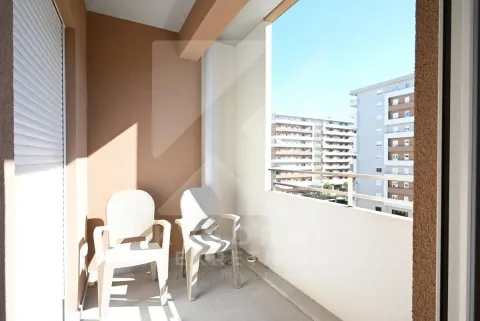 Covered balcony with two white chairs and a view of surrounding buildings. - image 2