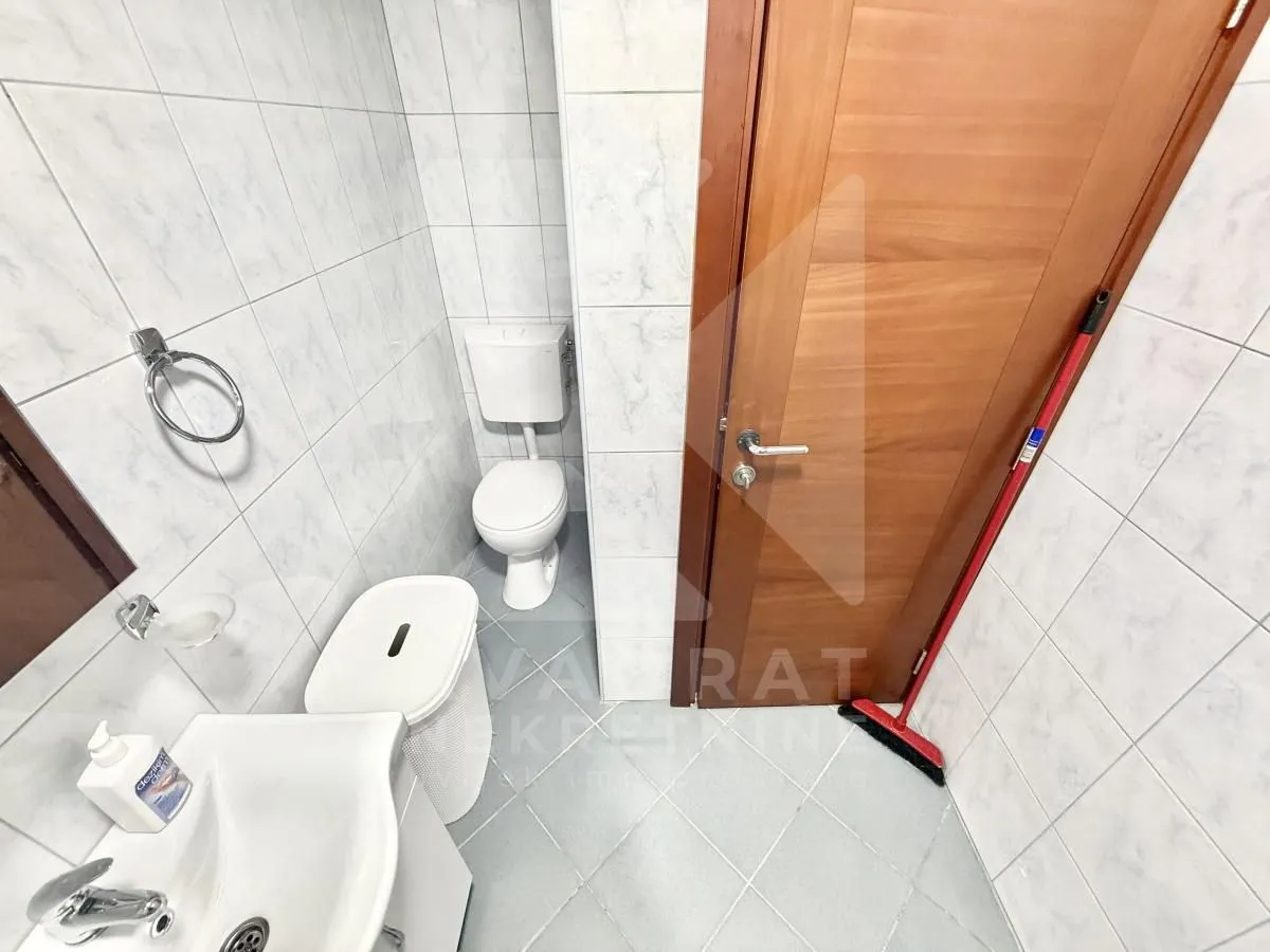 Small bathroom with white tiles, sink, and toilet.
