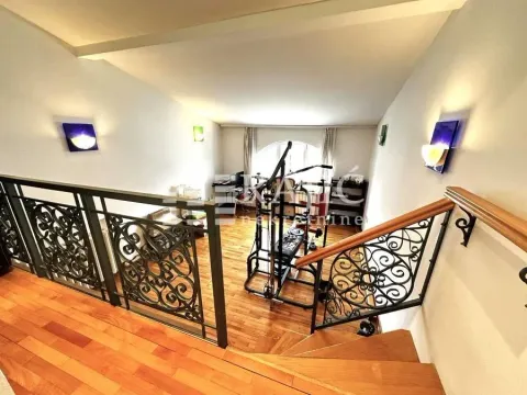 View from the stairs down to the living room with wooden flooring and fitness equipment. - image 7