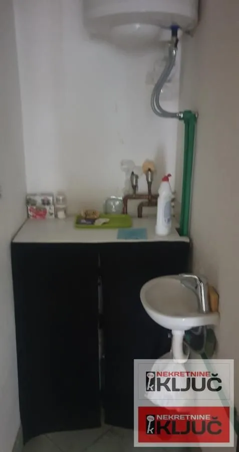Small bathroom with a washbasin and a water heater on the wall.