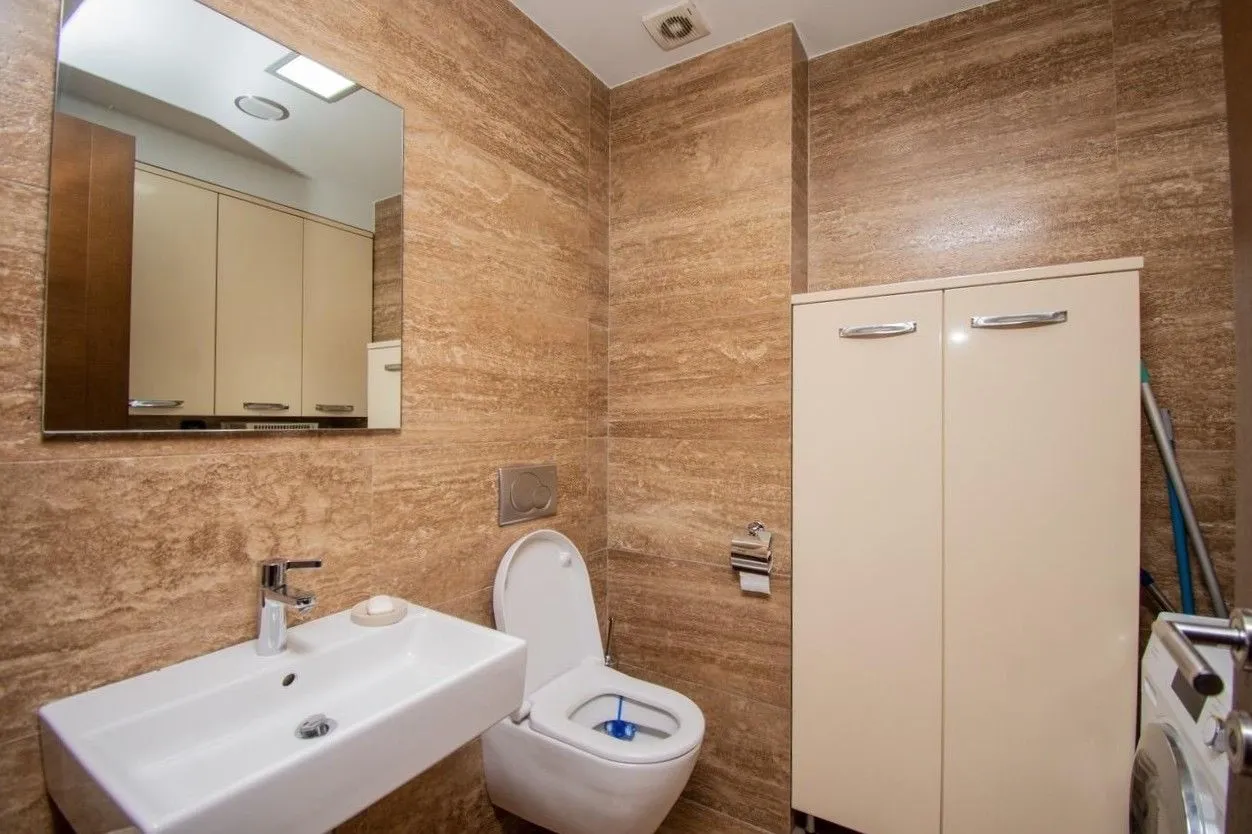 Moderne opremljeno kupatilo sa umivaonikom, wc šoljom i ugradnim ormarićima.