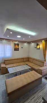 Living room with a corner sofa, coffee table, and drop ceiling with lighting. - image 2