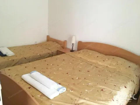 Bedroom with two wooden beds and a bedside table with a lamp. - image 11