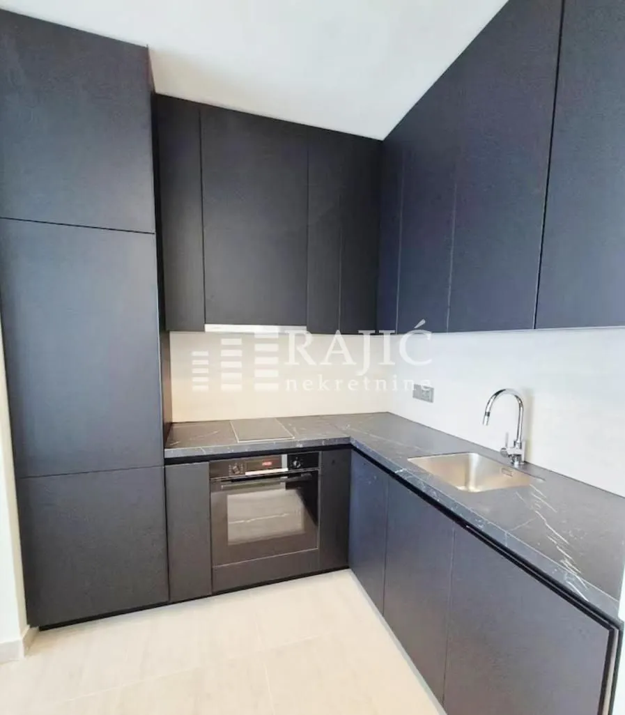 Modern kitchen with dark cabinetry and built-in appliances.