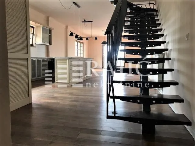 Unutrašnjost open-space prostora sa stepeništem i kuhinjom u pozadini.