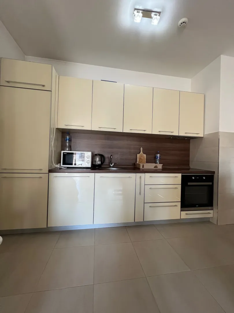 A view of a bright kitchen with fitted cabinets and appliances.