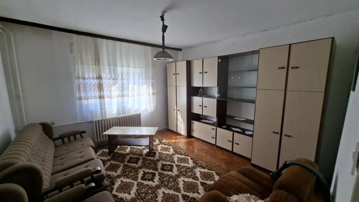 Dnevna soba sa garniturom za sedenje, velikim ormanom i tepihom.