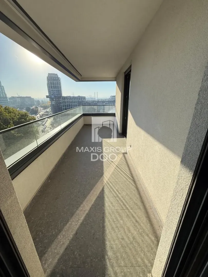 Prostrani balkon sa staklenom ogradom i pogledom na grad.