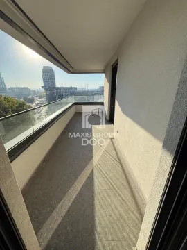 Prostrani balkon sa staklenom ogradom i pogledom na grad. - image 17