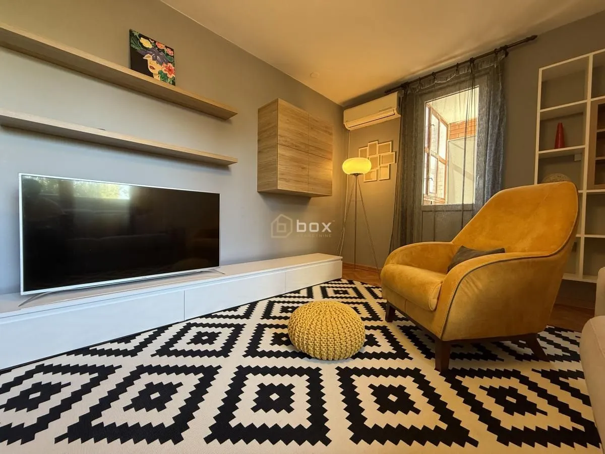 Living room with television, shelves and yellow armchair.