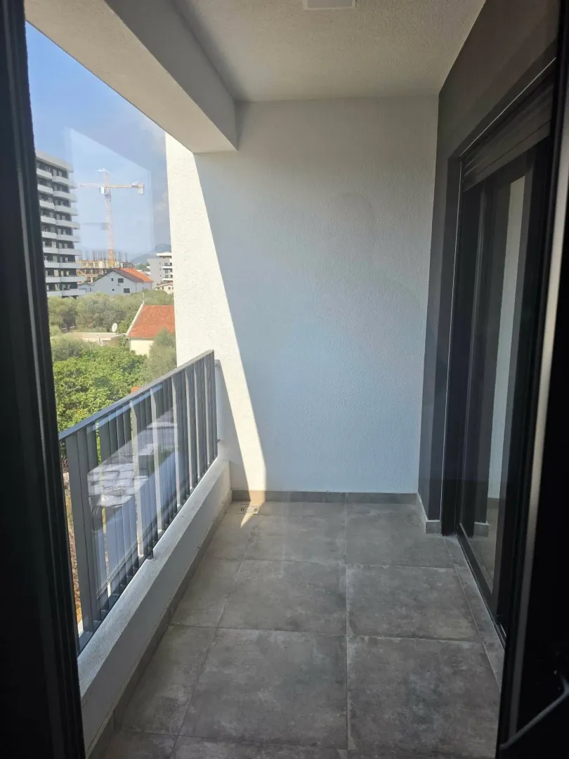 Moderan nenamješten balkon sa pločicama i pogledom na okolinu.