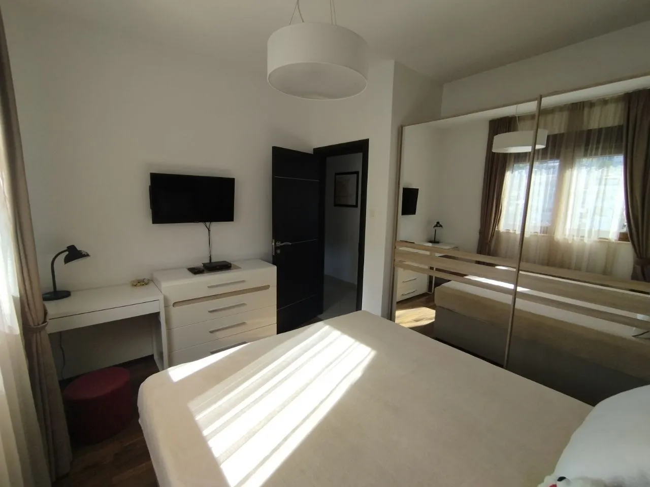 Furnished bedroom with a double bed, large mirrored wardrobe, and a desk.