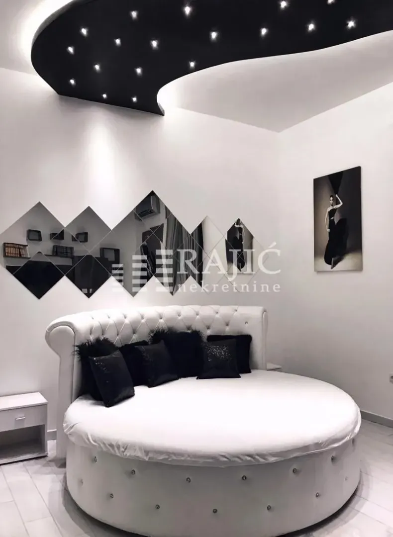 Modern bedroom with a round bed and decorative lighting.