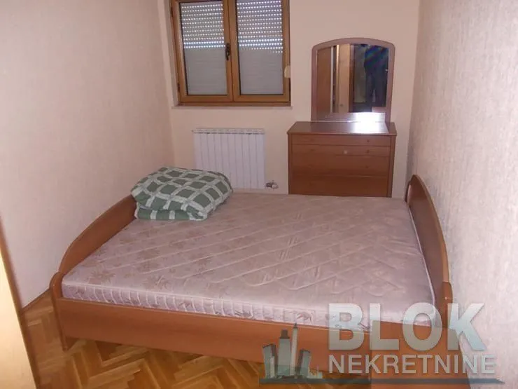 Furnished bedroom with a double bed and a dresser with a mirror.