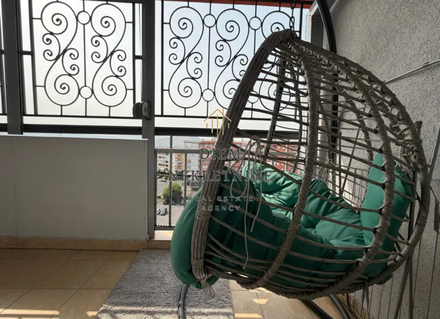 Natkrivena terasa sa visećom foteljom i pogledom na grad.