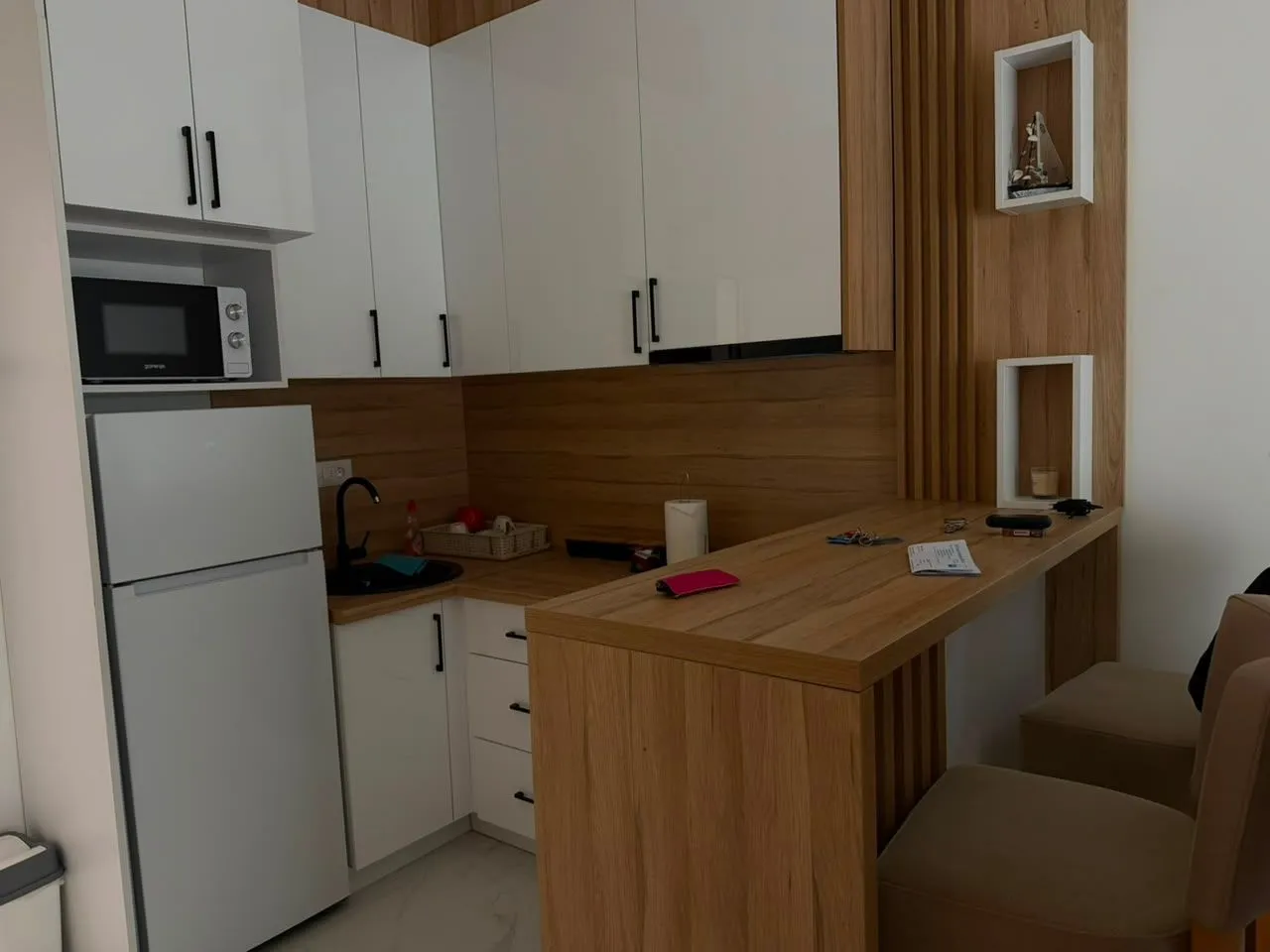 Modern kitchen with white cabinetry, wood paneling, and a bar counter with bar stools.