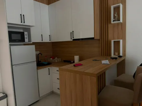 Modern kitchen with white cabinetry, wood paneling, and a bar counter with bar stools. - image 8