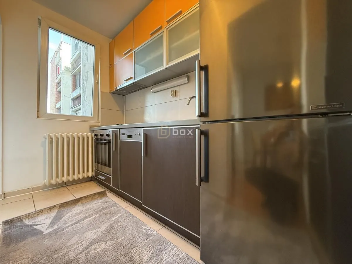 Small kitchen with wooden cabinetry, a refrigerator, and a window.