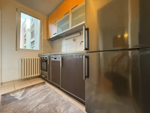 Small kitchen with wooden cabinetry, a refrigerator, and a window. - image 8