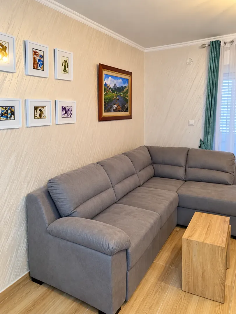Living room with a sectional sofa, coffee table, and paintings on the wall.