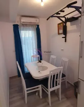 Trpezarija sa trpezarijskim stolom i stolicama, klima uređajem i vratima koja vode na balkon. - image 5