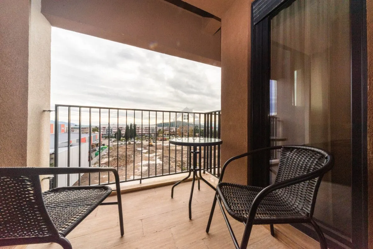 Natkriveni balkon sa garniturom za sjedenje i pogledom na okolinu.