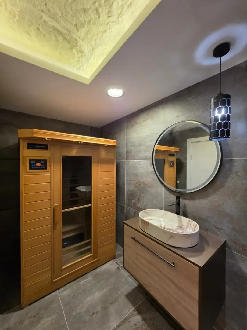 Bathroom equipped with a washbasin, mirror, and a private wooden sauna.
